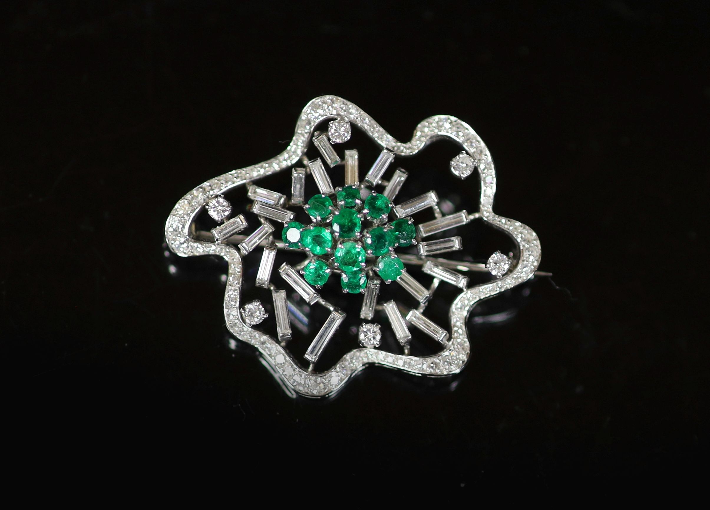 A white gold, emerald and diamond set open work modernist brooch